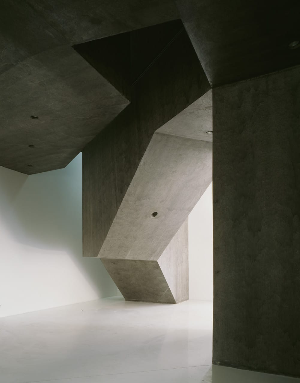 Angular concrete passage and compressed vertical opening inside Casa dos Cubos in Tomar.