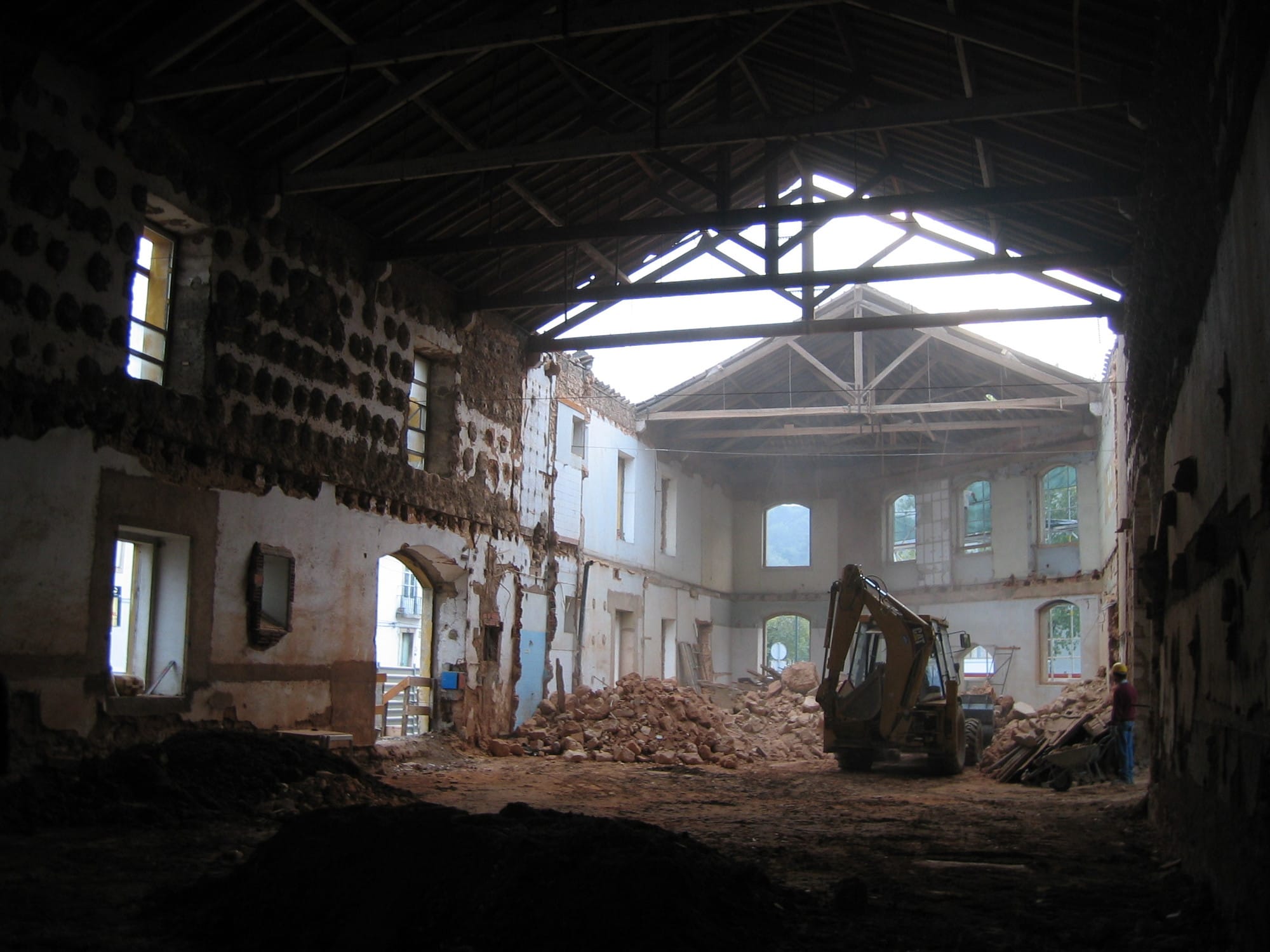 Casa dos Cubos during demolition, with an excavator and rubble inside the stripped former industrial building.