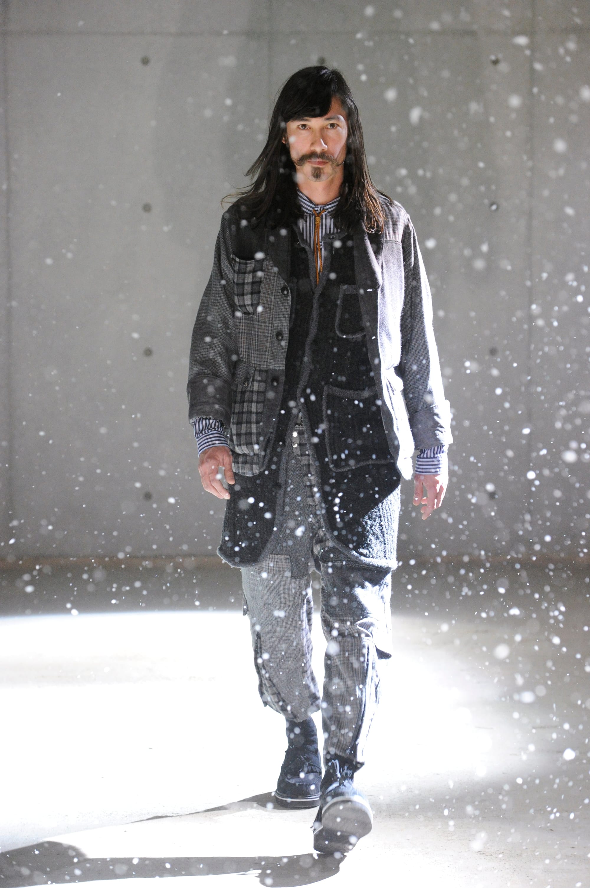 White Mountaineering Wilderness Outfitters look 20: grey hunting jacket over a jacquard knit and dark trousers.