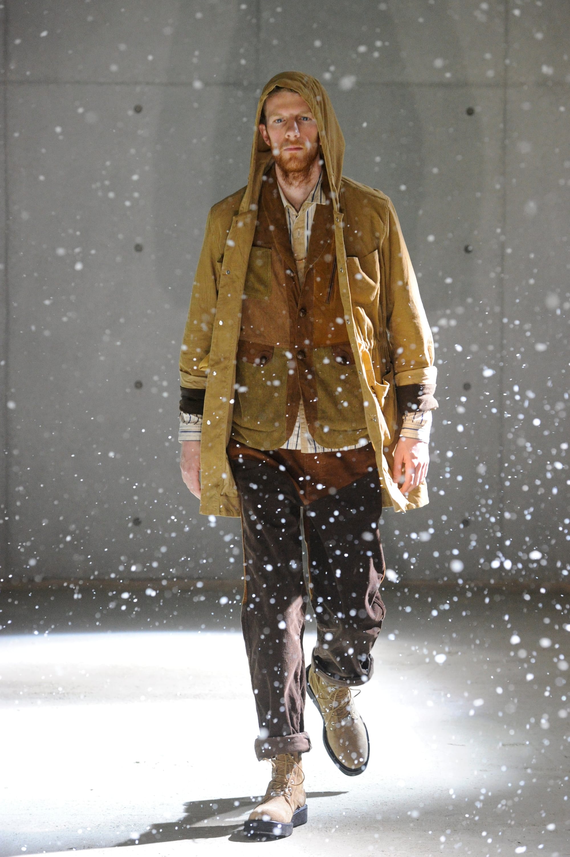 White Mountaineering Wilderness Outfitters look 22: black utility vest, plaid shirt, fur hat and layered field apron.