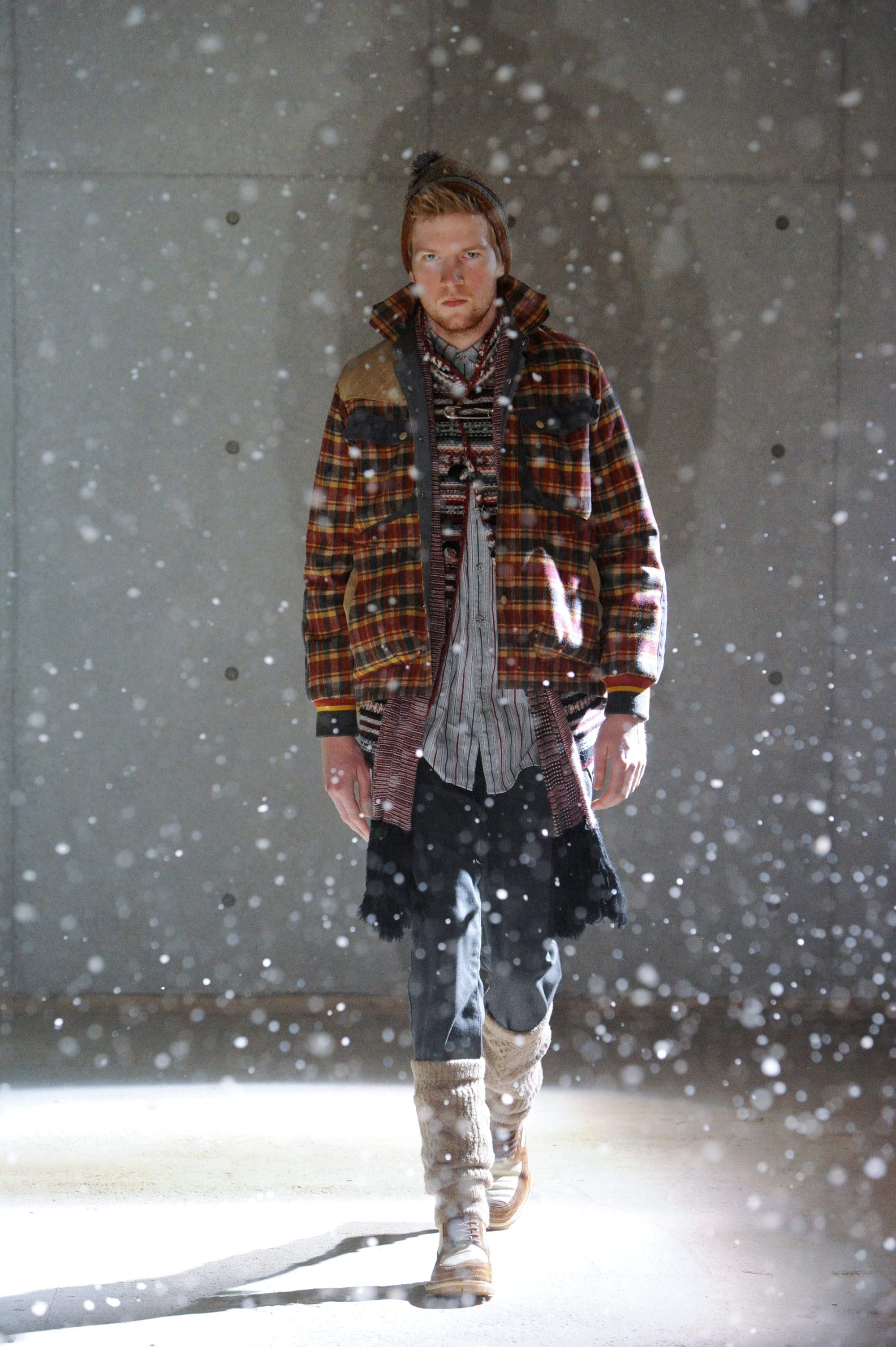 White Mountaineering Wilderness Outfitters look 26: black fur-trimmed vest over a grey field suit with hunting pockets.