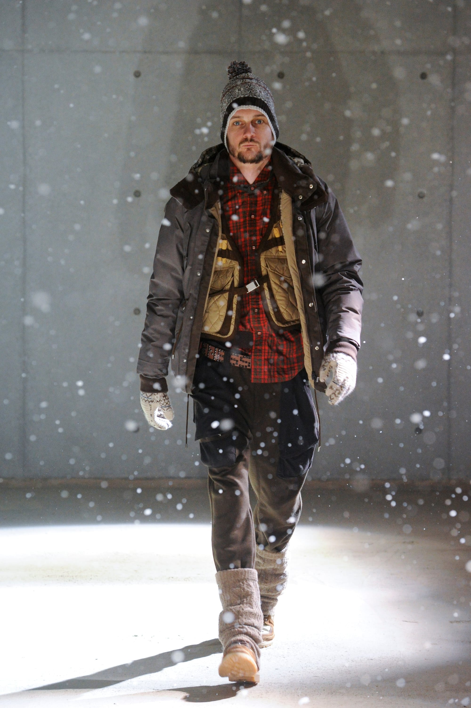 White Mountaineering Wilderness Outfitters look 27: grey patterned hood, black utility vest and dark field trousers.