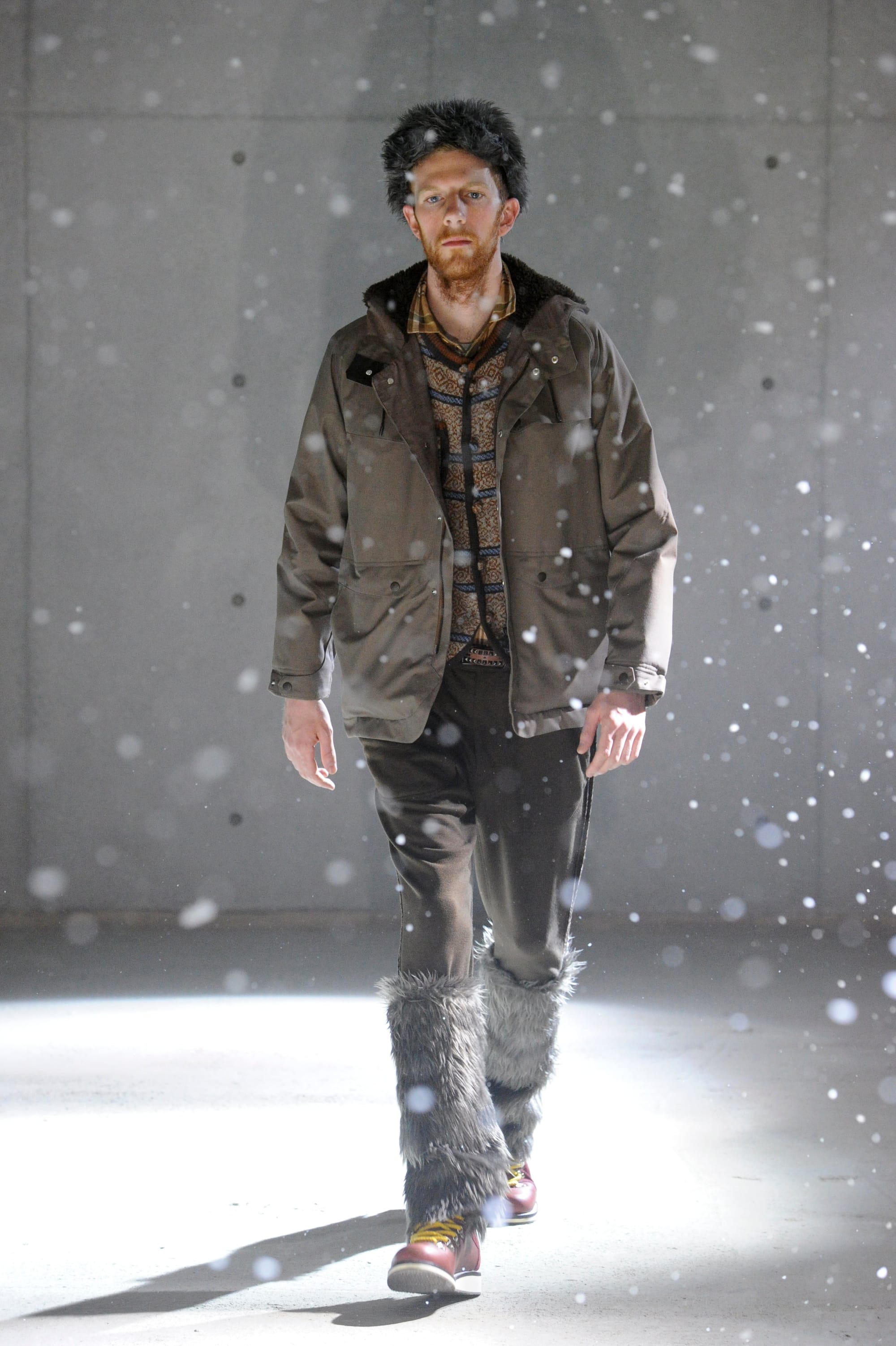 White Mountaineering Wilderness Outfitters look 28: grey knit layers, black cap and mixed plaid outerwear.