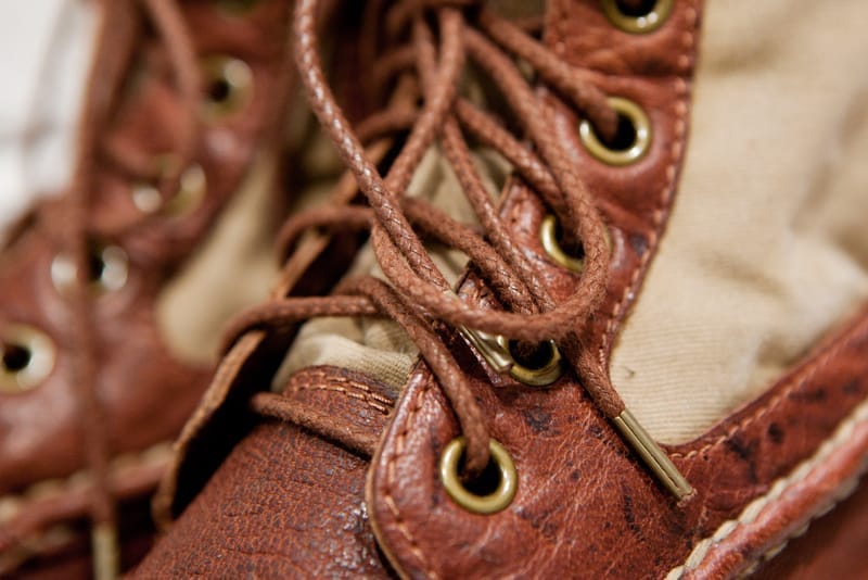 Close view of brown leather laces, brass eyelets and tan Italian canvas on the visvim Grizzly Boots Mid-Folk.