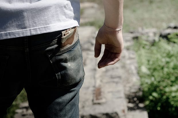 Close view of dark Deadwood denim with contrast back-pocket fabric and a small leather waistband label.