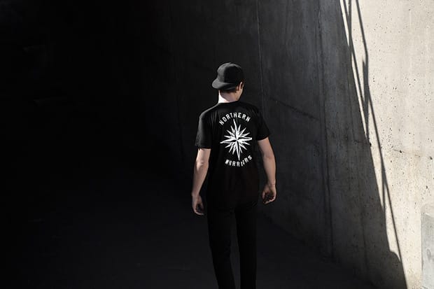 Rear view of a black Deadwood Northern Warriors graphic T-shirt in a concrete passage.
