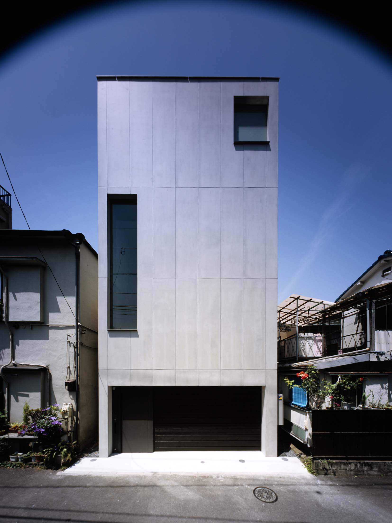 Narrow concrete street facade of 2COURTS HOUSE on a dense Tokyo residential site.