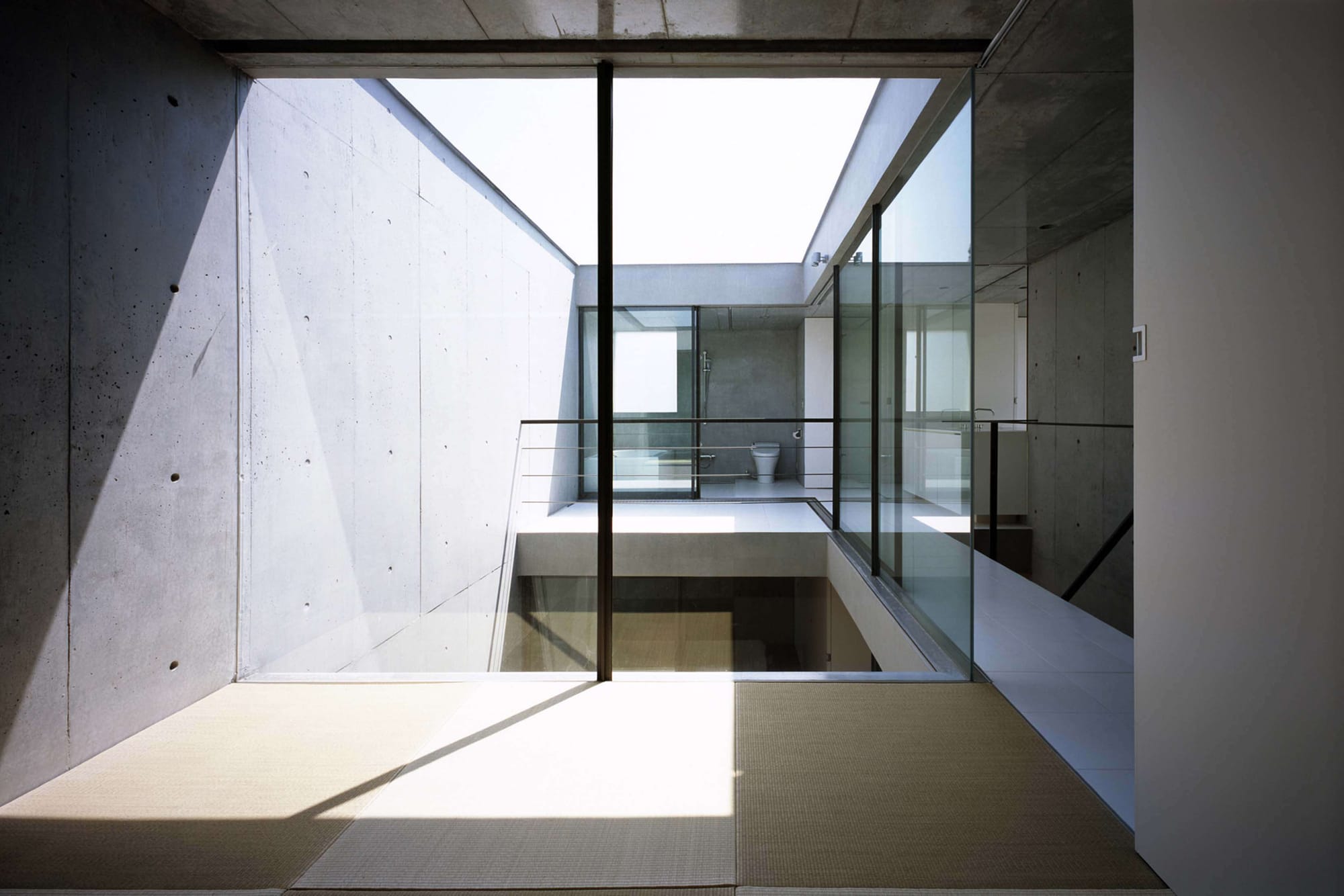 Tatami room overlooking the concrete courtyard and bathroom level of 2COURTS HOUSE.