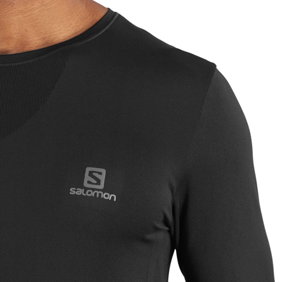 Worn close-up of the black Salomon Sense Pro men's long-sleeve top, showing the reflective chest logo, smooth shoulder panel, and triangular mesh collar vent. Retail item code SAL01RO and...