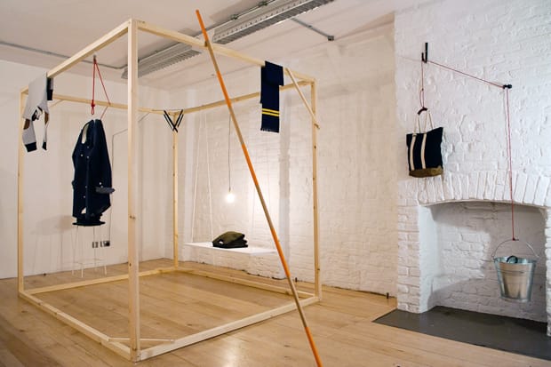 Wide view of the Silent Ventures London pop-up installation with suspended garments, bag and metal bucket.