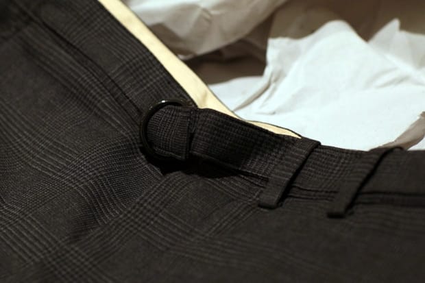 Close view of the black D-ring waist adjuster on the Homage to 221B gun-club-check shorts.