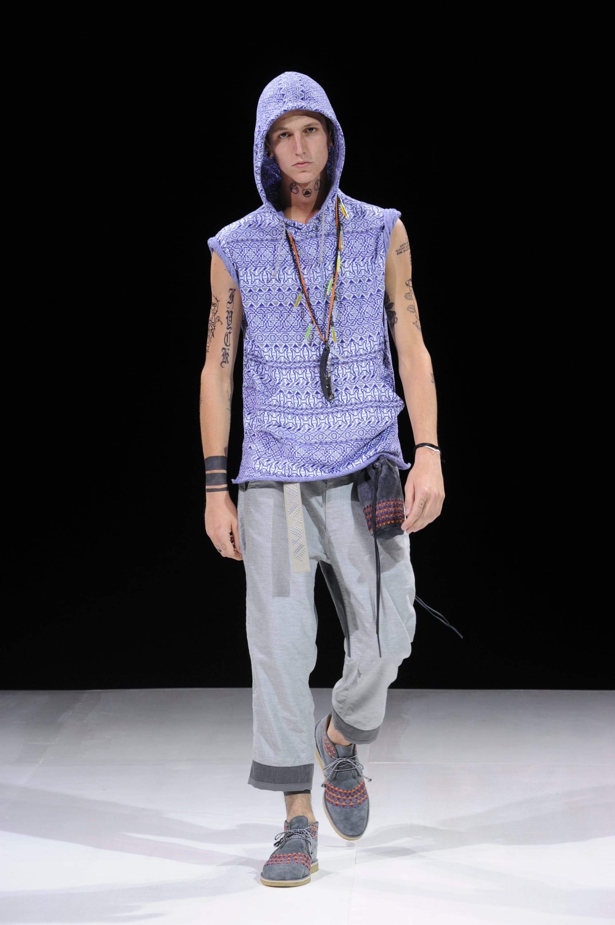 Model in a lavender sleeveless hooded knit top and pale grey cuffed trousers.