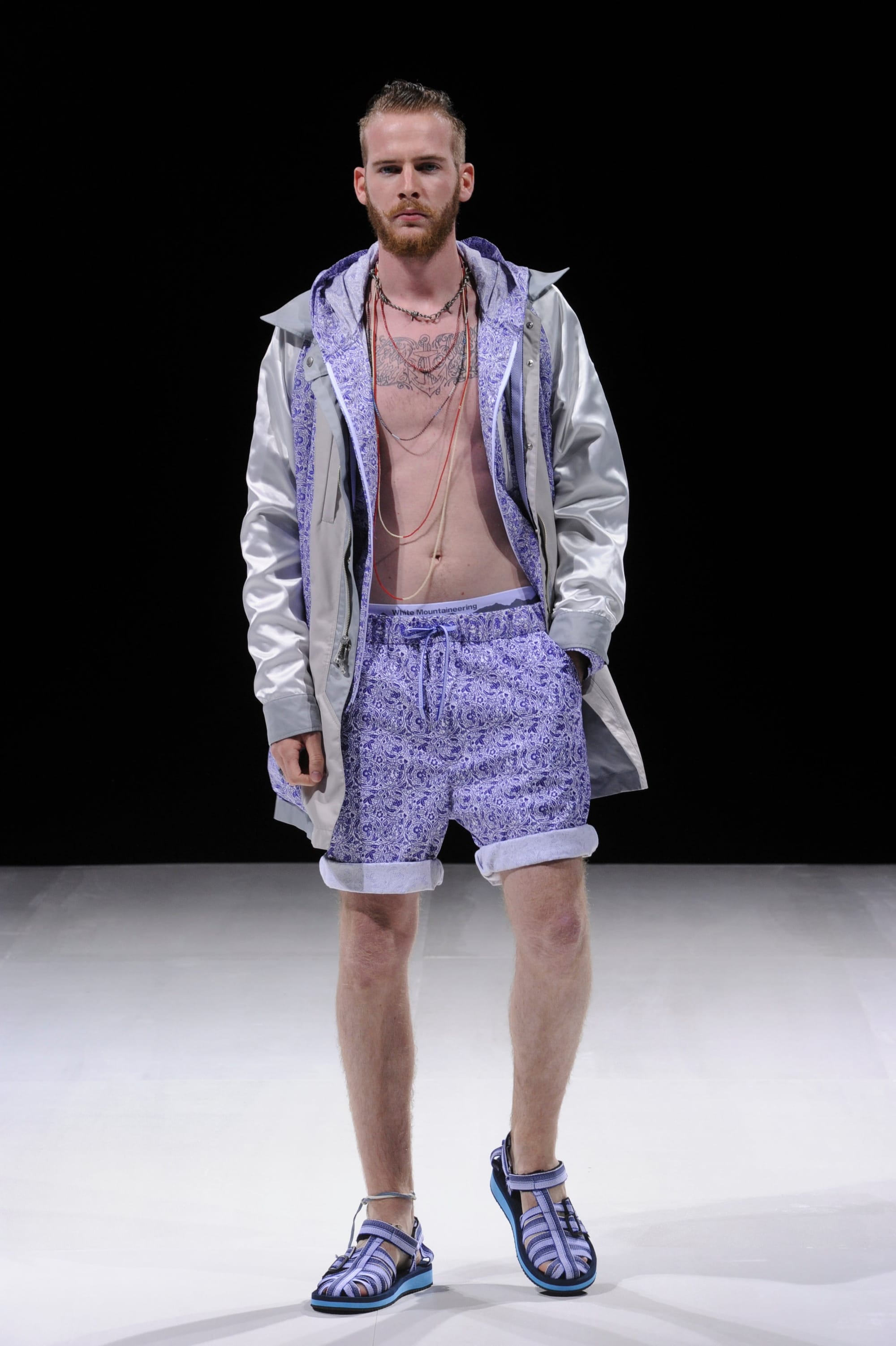 Model in a silver hooded coat and lavender patterned shorts.