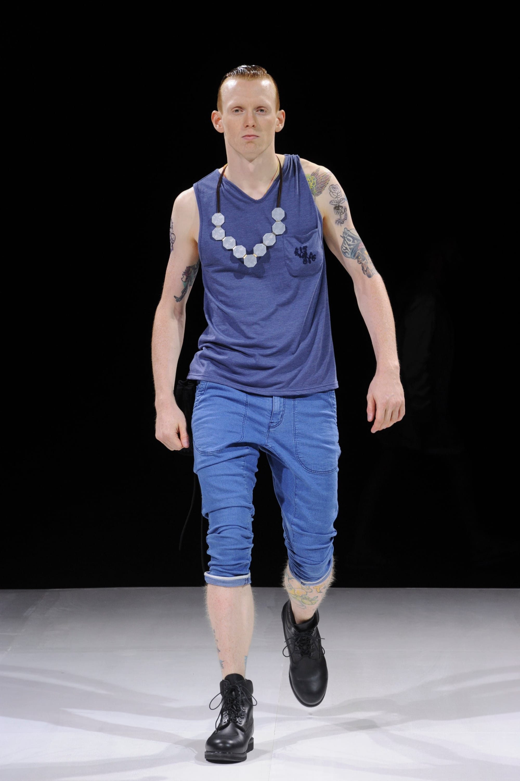 Model in a navy tank top and bright blue cropped trousers.