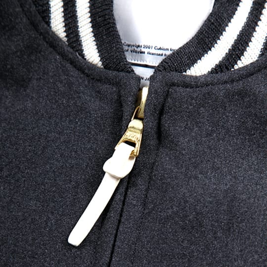 Close view of the striped collar and gold zipper with white leather pull on the charcoal visvim Windstopper Varsity Jacket.