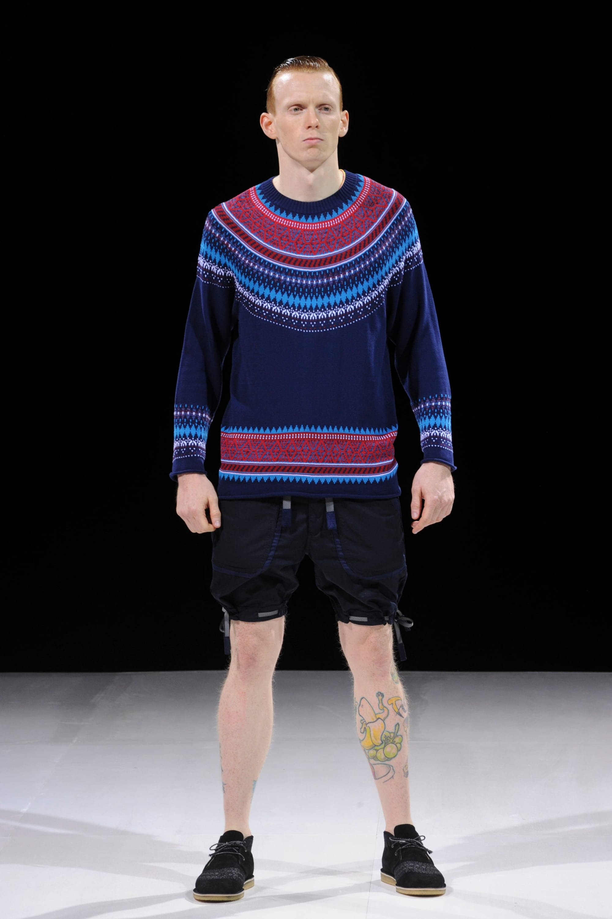 Model in a navy Fair Isle sweater and black layered shorts.