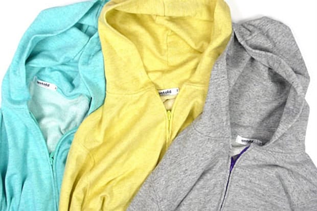 UNTOLD zip hoodies in turquoise, yellow and heather grey, arranged to show their hoods, labels and contrast zippers.