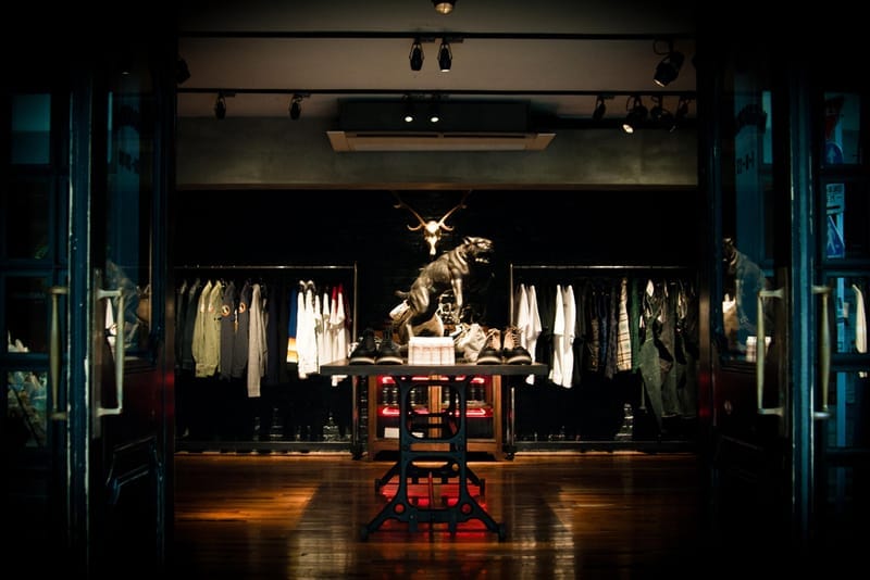 View through the NEIGHBORHOOD Shibuya entrance toward clothing racks, boots, a panther statue and a deer skull.