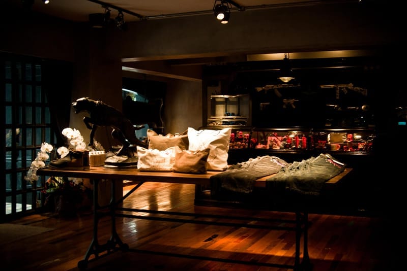 NEIGHBORHOOD Shibuya display table with canvas bags, boots, denim and illuminated collectibles.