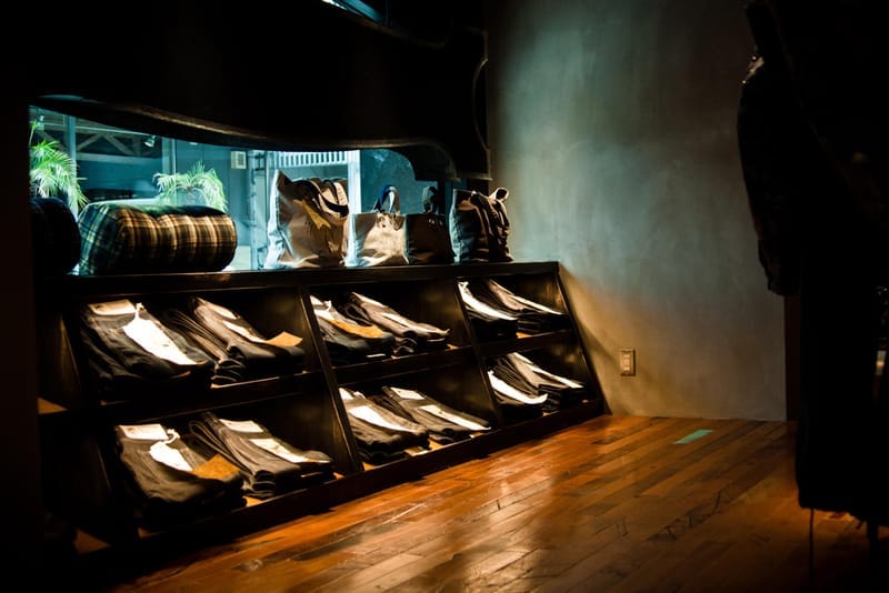 Sloped denim shelves and canvas bags inside the NEIGHBORHOOD Shibuya store.