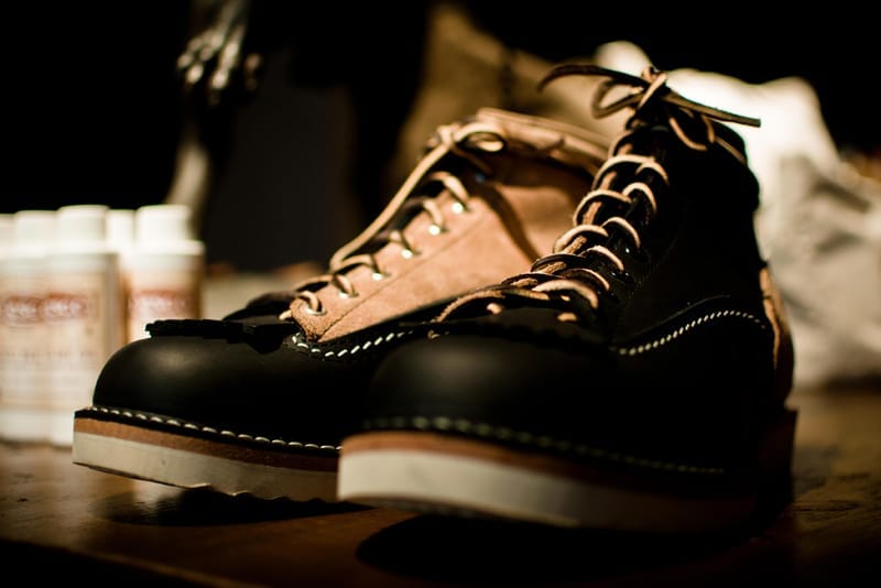 Black and tan lace-up leather boots with white welt stitching on a store display.