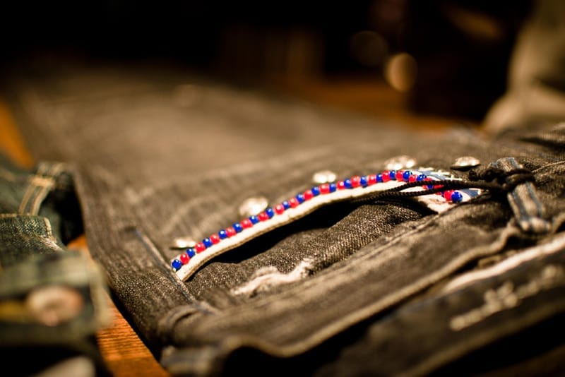 Distressed black denim pocket detail with red, white and blue beaded trim.