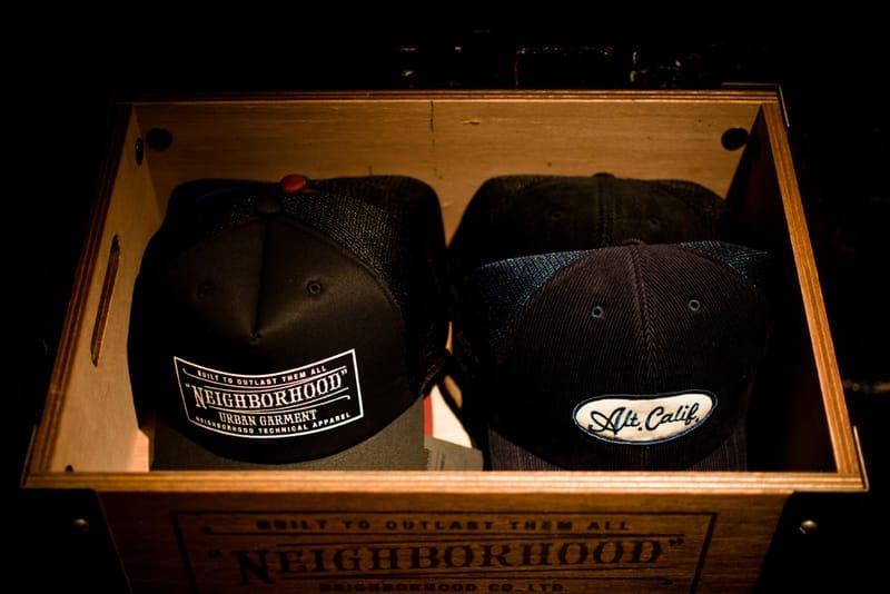 NEIGHBORHOOD Urban Garment and Alt. Calif caps displayed in a branded wooden crate.