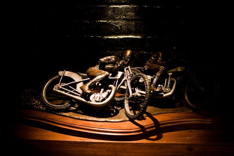 Vintage-style motorcycle racer sculptures on a wooden shelf inside NEIGHBORHOOD Shibuya.