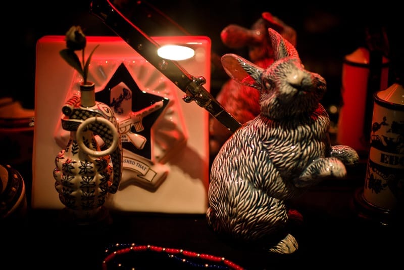 Rabbit sculpture, ceramic grenade and graphic display objects under red light.