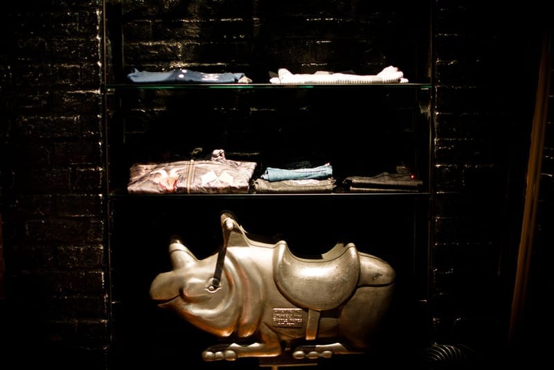 Metallic rhinoceros sculpture below shelves of folded NEIGHBORHOOD clothing.