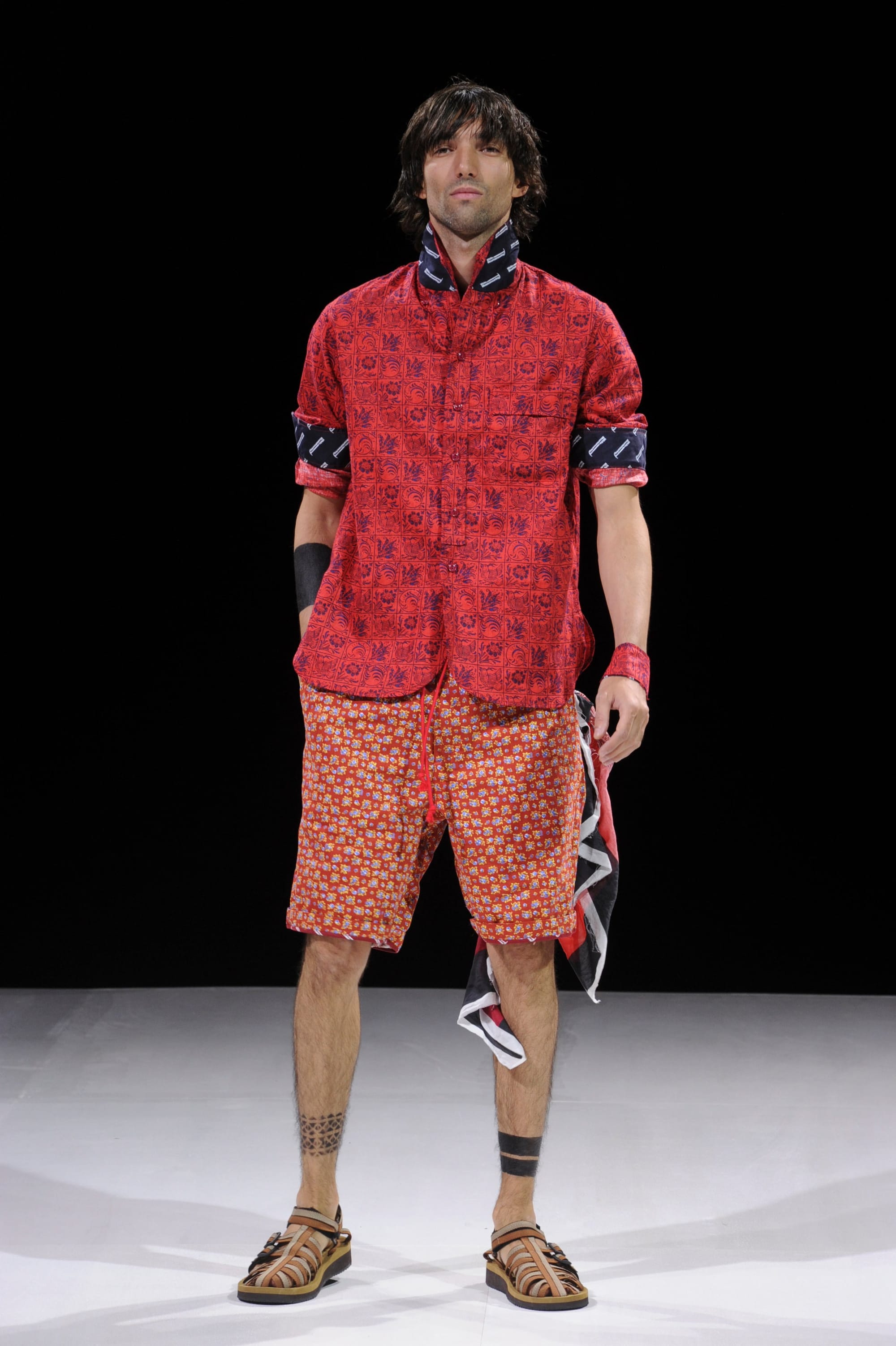 Model in a red patterned short-sleeve jacket and orange patterned shorts.