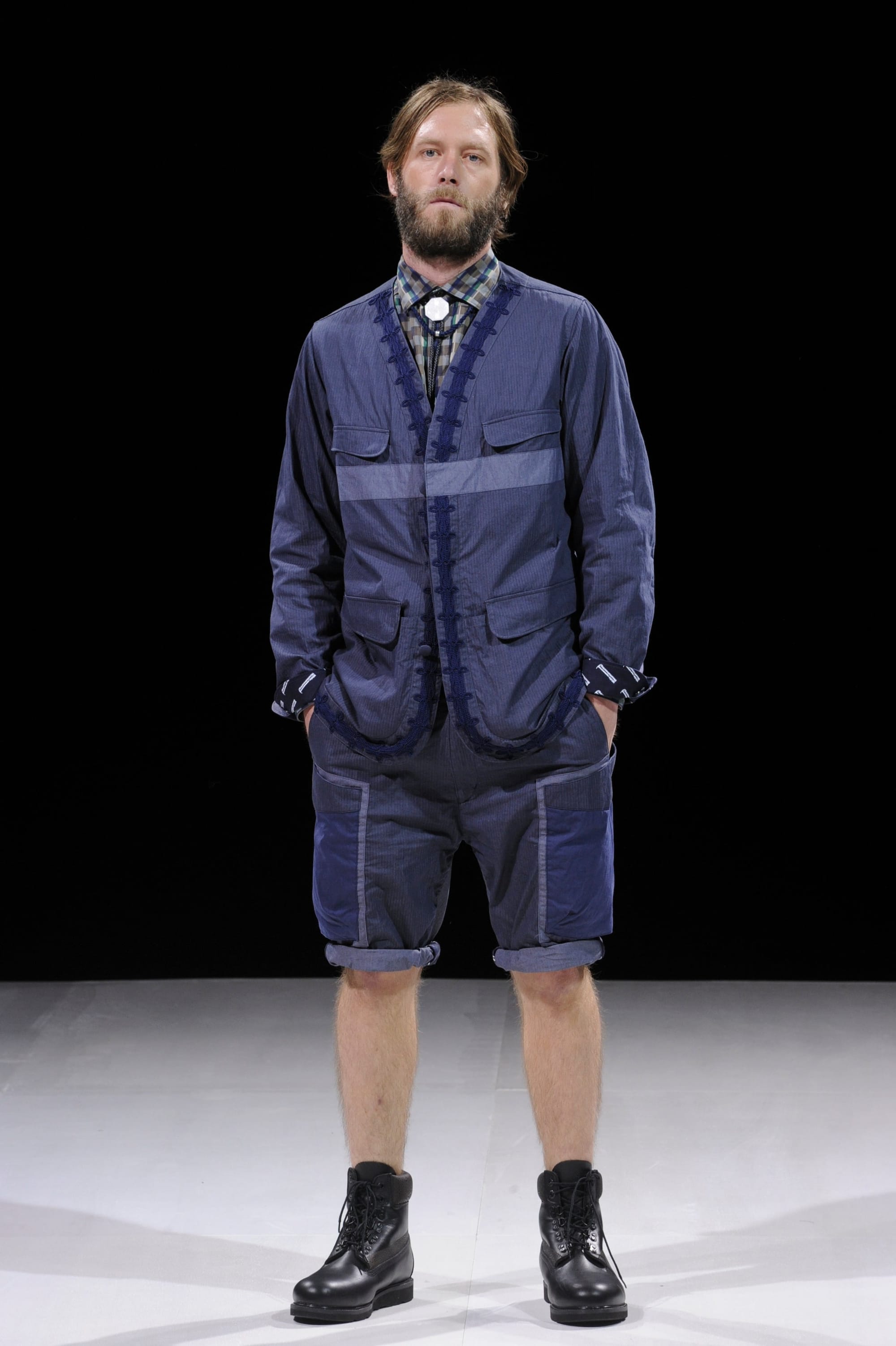 Model in a navy workwear jacket and matching shorts with dark geometric trim.