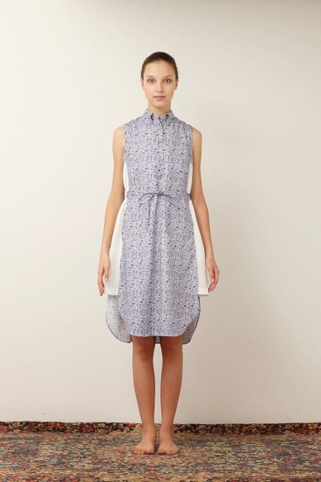 White Mountaineering womenswear model in a sleeveless blue-and-white patterned shirt dress with white side panels.