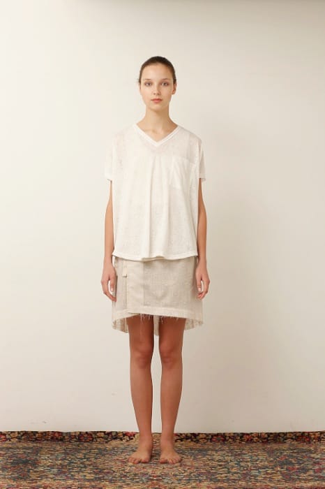 White Mountaineering womenswear model in a loose white V-neck top and cream embroidered skirt.