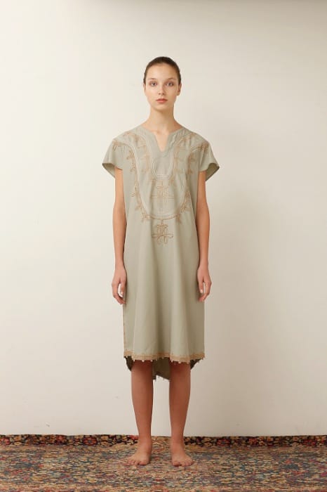 White Mountaineering womenswear model in a pale olive embroidered V-neck dress with a lace-trimmed hem.