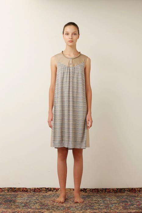 White Mountaineering womenswear model in a sleeveless grey striped dress with a gathered neckline.