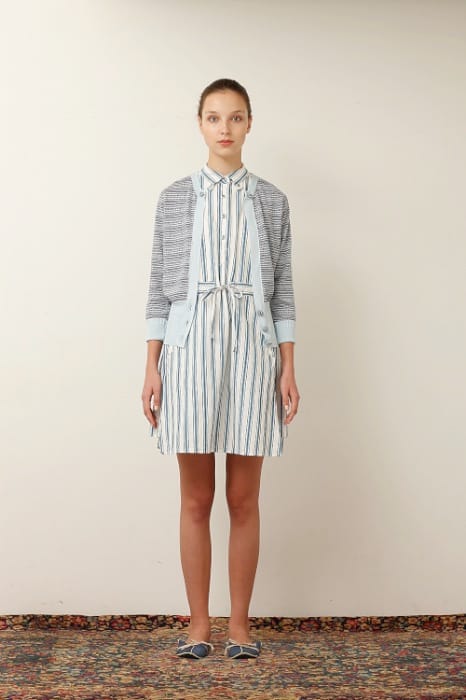 White Mountaineering womenswear model in a blue-and-white striped shirt dress, grey cardigan and blue flats.