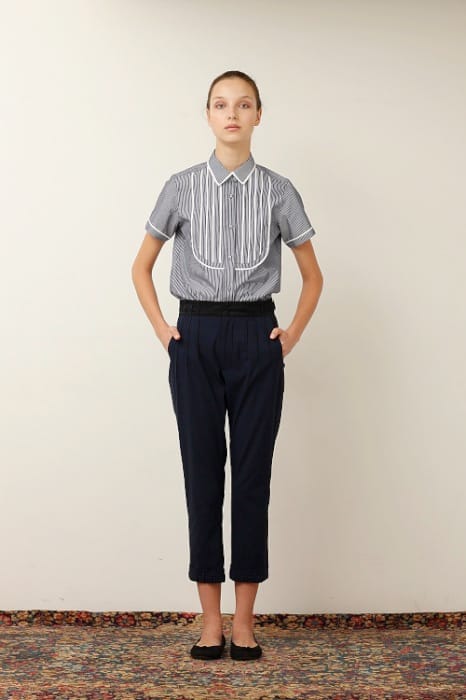 White Mountaineering womenswear model in a grey striped bib shirt and navy cropped trousers.