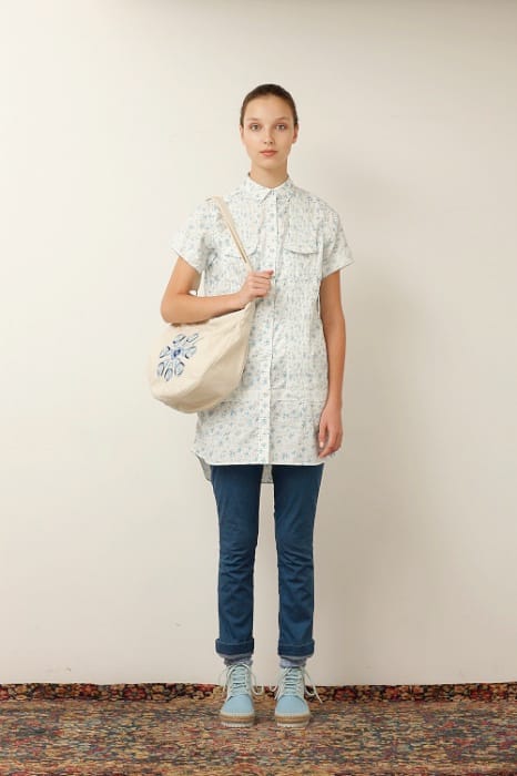 White Mountaineering womenswear model in a pale floral tunic, blue jeans, canvas shoulder bag and light blue boots.