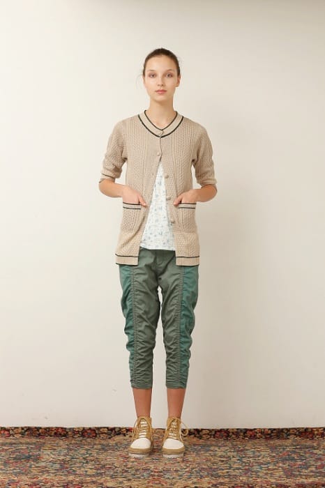 White Mountaineering womenswear model in a beige cardigan, floral blouse and cropped green utility trousers.