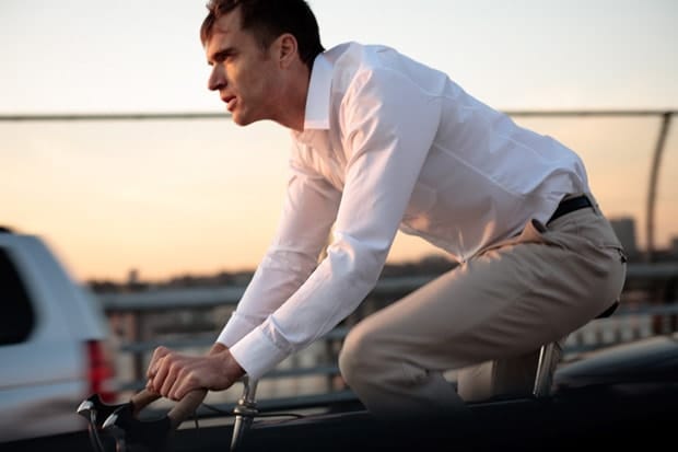 Cyclist wearing Outlier Khaki OG Pants with a white shirt during an evening city ride.