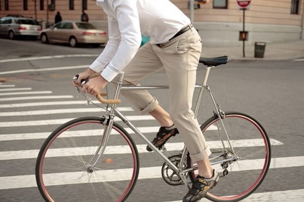 Cyclist demonstrates the four-way-stretch Outlier Khaki OG Pants on a city street.