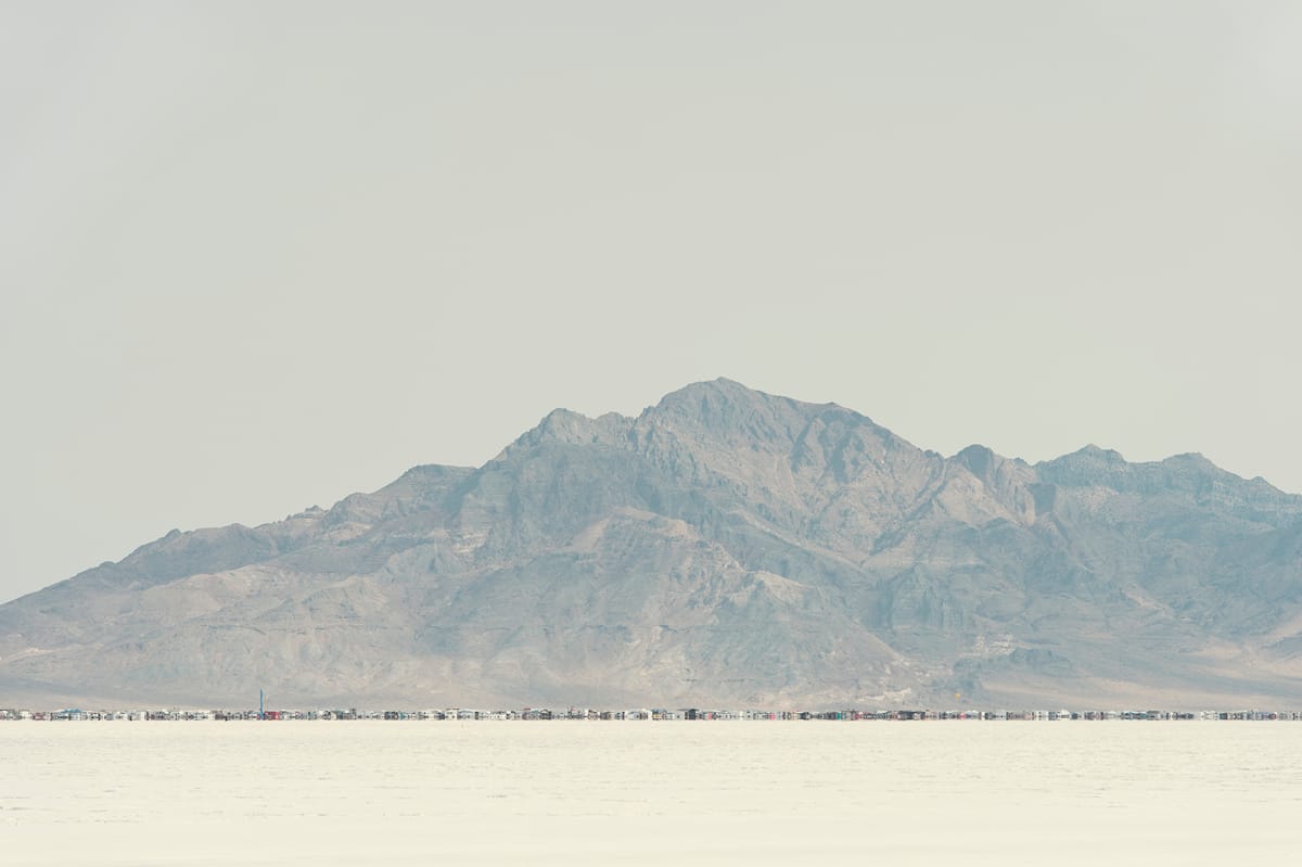Wide view across the Bonneville Salt Flats from the far tracks to the long rows of SpeedWeek pits and mountains.