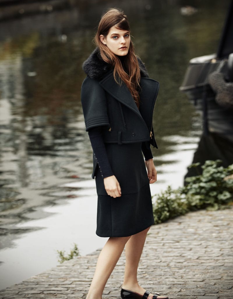Kia Low standing beside the canal in a dark Marni jacket and skirt with a John Smedley turtleneck.