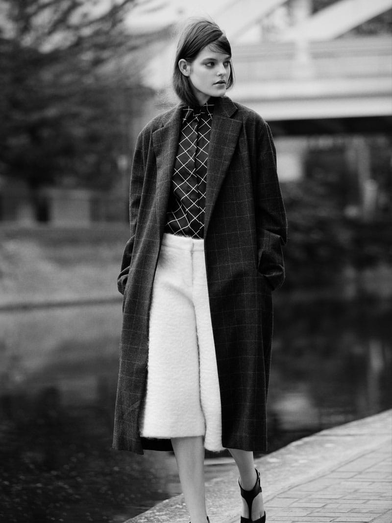 Kia Low in a checked Hobbs coat, Holly Fulton grid shirt and white J JS Lee trousers beside the canal.