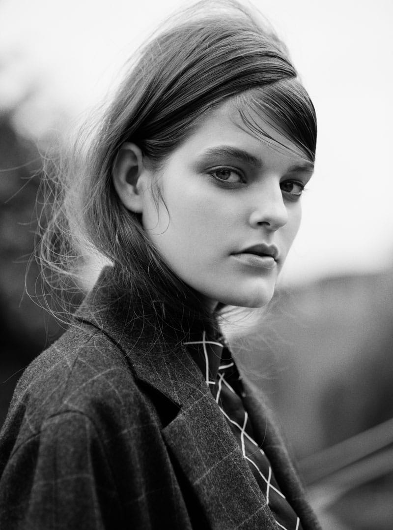 Black-and-white close portrait of Kia Low in a Hobbs coat over a Holly Fulton grid-pattern shirt.