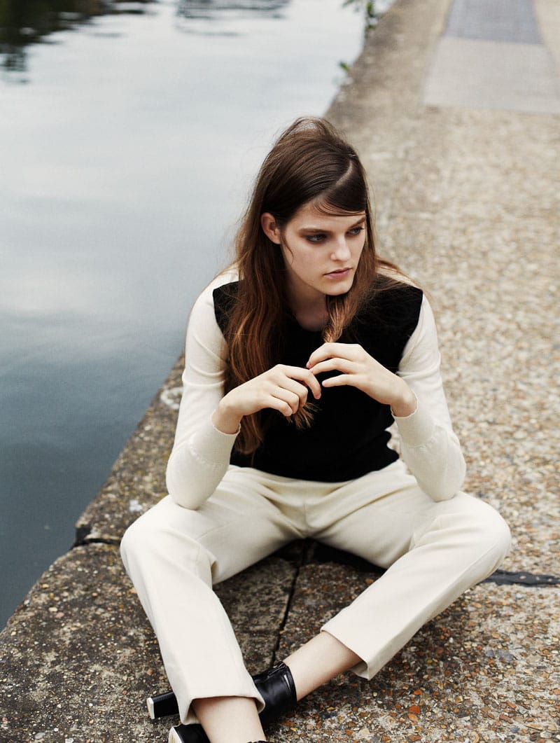 Kia Low seated cross-legged beside the canal in a black-and-cream Paul Smith look.
