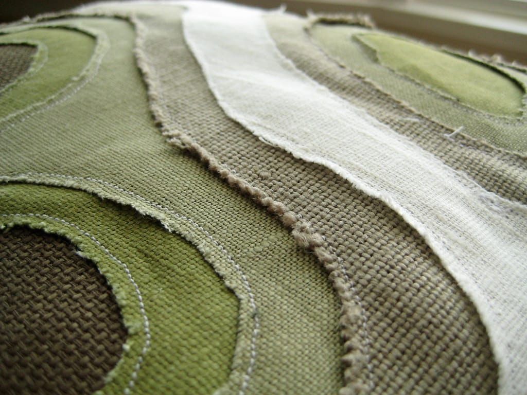 Close-up of olive, taupe and white reverse-applique fabric contours on Marnie Karger's Crafterall Topo Pillow.