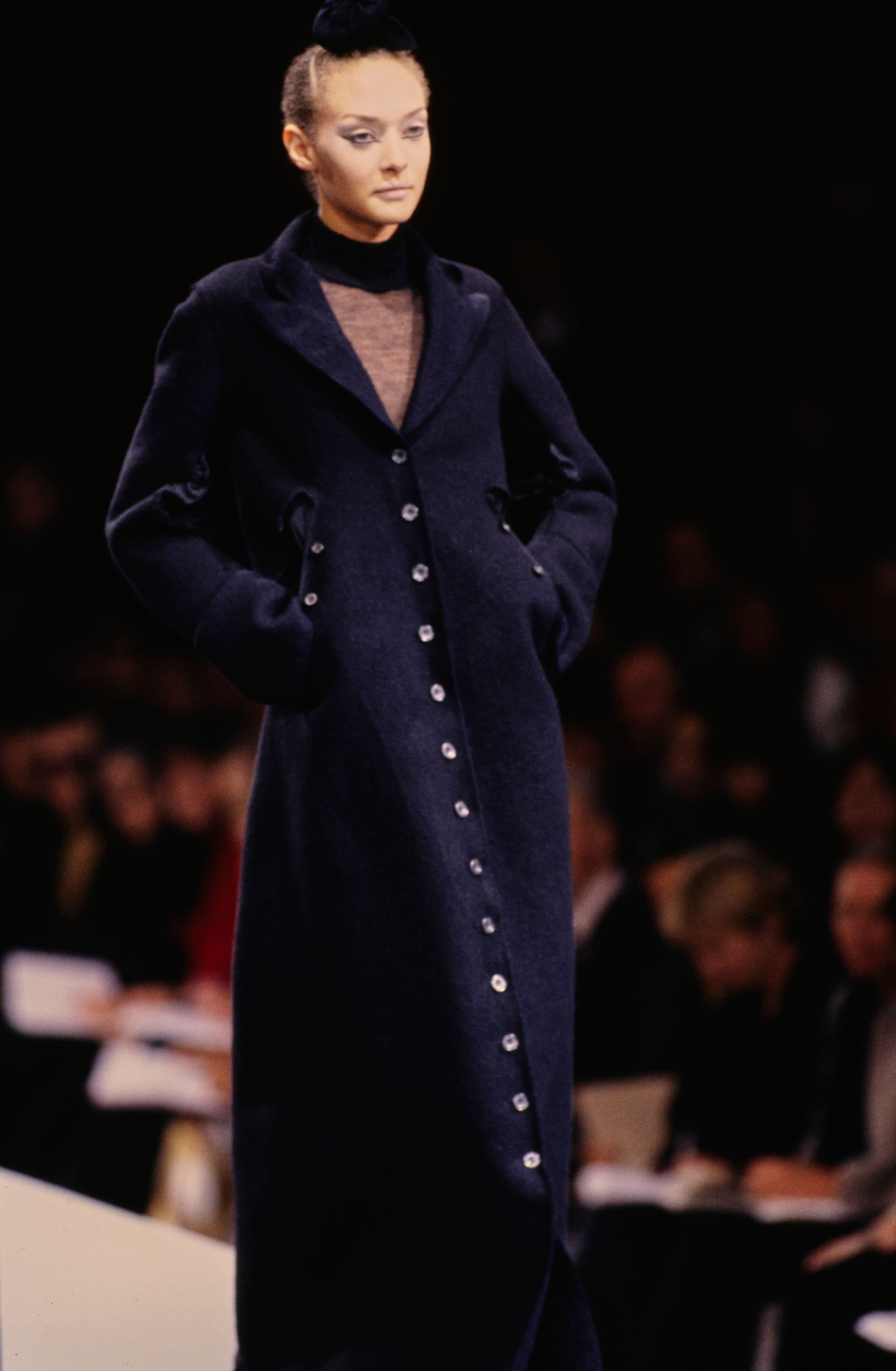 Yohji Yamamoto Fall 1995 detail 9: Dark fitted long coat with a line of small buttons over a sheer V-neck layer.