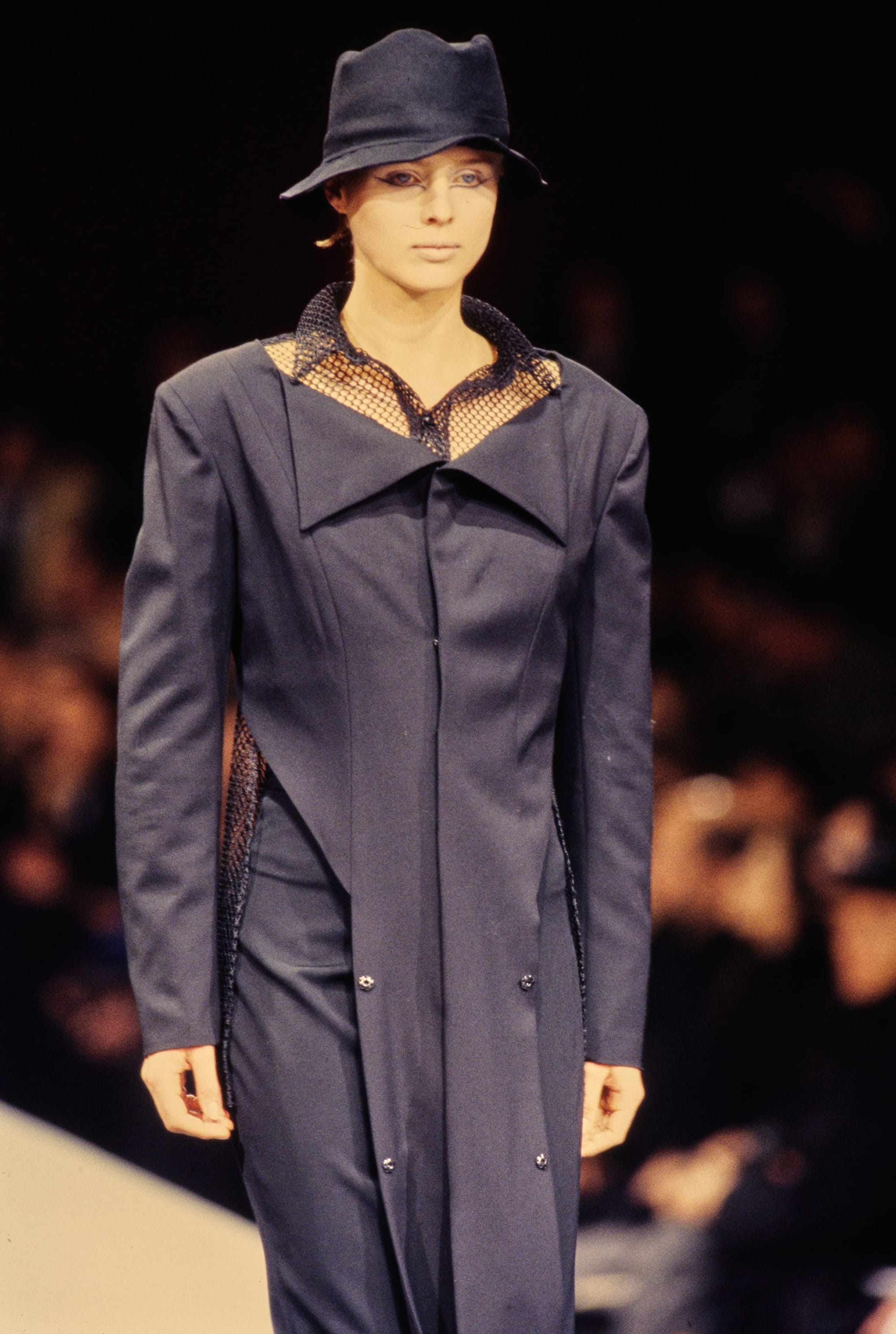 Yohji Yamamoto Fall 1995 detail 23: Close view of a navy jacket with a broad folded collar and black fishnet at the neck.
